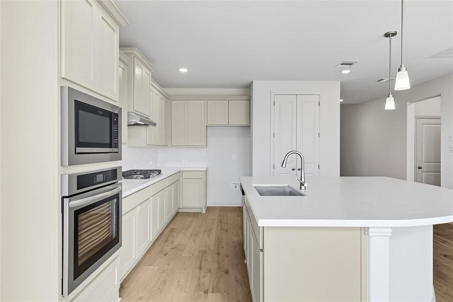 Kitchen featuring stainless steel appliances, light wood-type flooring, pendant lighting, recessed lighting, and a center island with sink Kitchen featuring stainless steel appliances, light wood-type flooring, pendant lighting, recessed lighting, and a center island with sink
