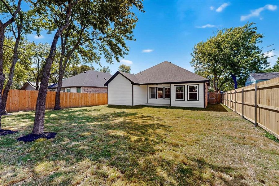 Back of property with a fenced backyard and roof with shingles