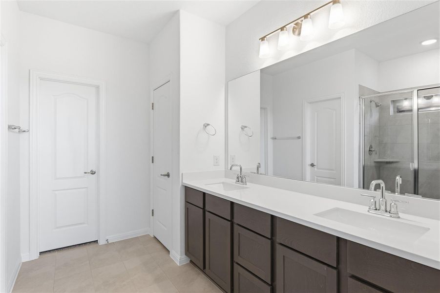 Bathroom featuring double vanity, a shower stall, and light tile patterned flooring
