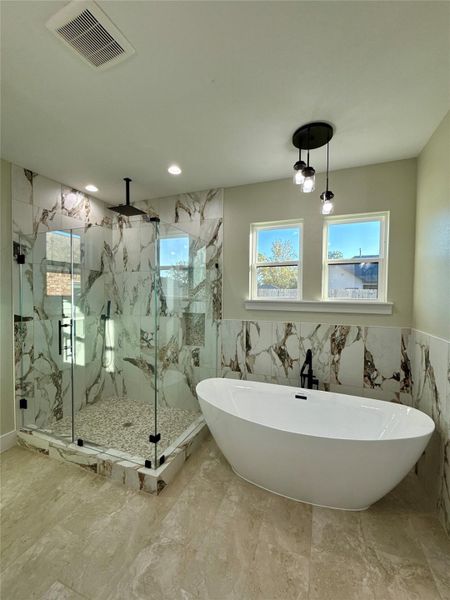 This modern bathroom features a spacious glass-enclosed shower with marble-style tile and a sleek freestanding bathtub. Natural light pours in through two windows, complementing the contemporary pendant lighting. This modern bathroom features a spacious glass-enclosed shower with marble-style tile and a sleek freestanding bathtub. Natural light pours in through two windows, complementing the contemporary pendant lighting.