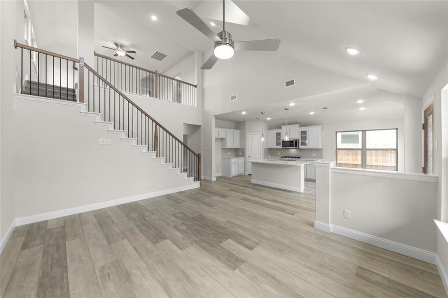 Unfurnished living room with high vaulted ceiling, light hardwood / wood-style floors, and ceiling fan