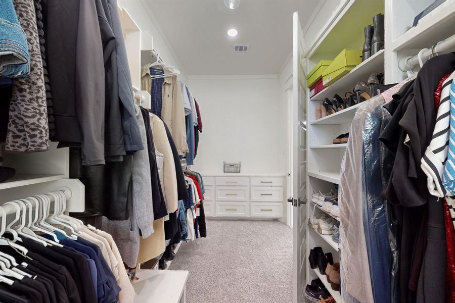 Primary walk in closet with built in drawers at one end and a personal vanity at the other! There's even more room for custom cabinets above the drawers. Lovely storage and organization.