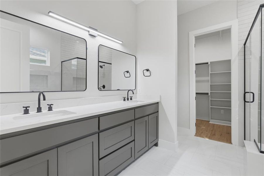 Bathroom featuring a dual vanity with a light-toned countertop, matte black hardware, and two framed mirrors Bathroom featuring a dual vanity with a light-toned countertop, matte black hardware, and two framed mirrors