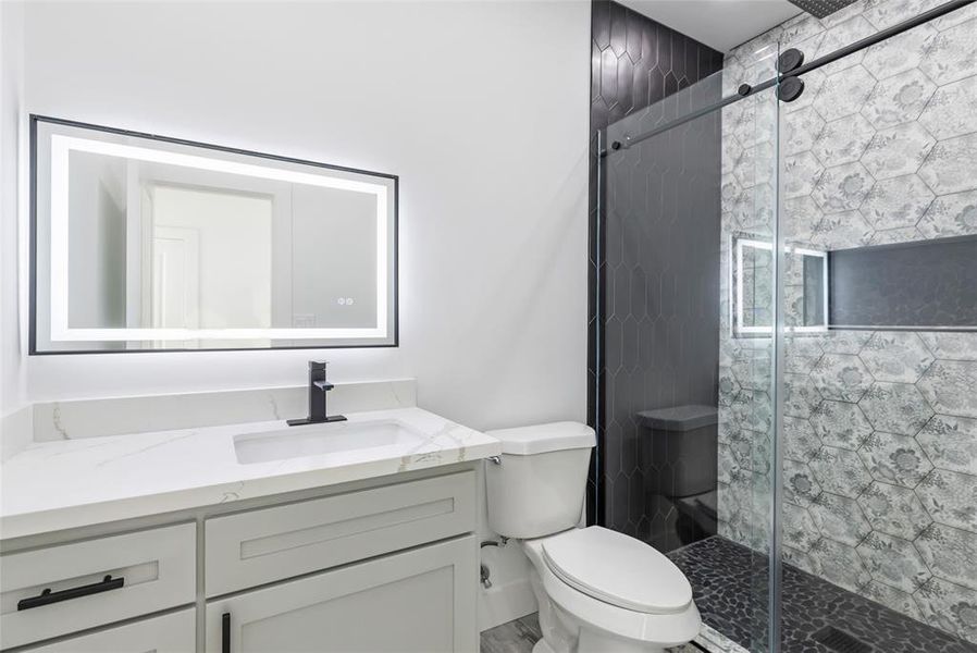 WOW! This secondary bathroom offers a walk-in shower with Gorgeous tile work, Quartz counter with a custom wood cabinet and an Amazing frameless wall mirror with LED lighting.