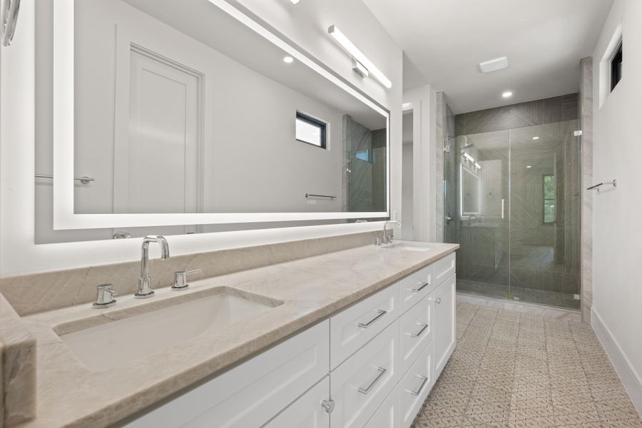 Gleaming stone countertops and a modern glass shower elevate this refined bathroom space.