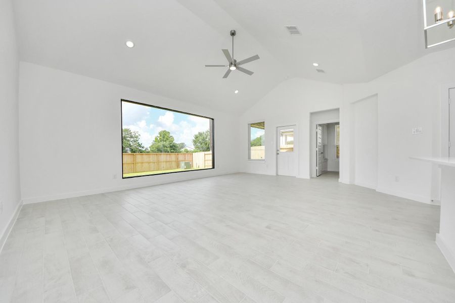 Welcome family and guests to your charming living room! With its high ceilings, recessed lighting, ceiling fan, custom paint, beautiful flooring, and large windows that let in abundant natural light, this room is perfect for gatherings.