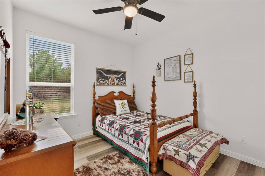 Bright interior space featuring wood-finish flooring, a ceiling fan, and a large window with horizontal blinds