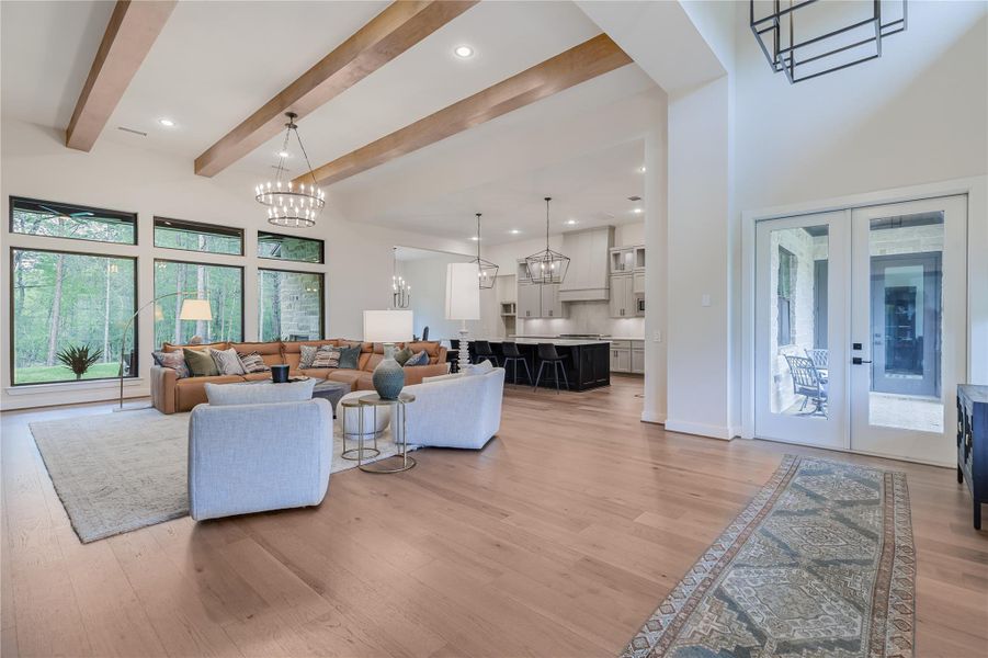 The walls of floor to ceiling windows bring the outside vistas inside further enhancing the tranquil ambience in the impressive open concept living space of the home.  Imposing wooden ceiling beams connect with the warm wooden floors and the neutral organic palette compliments the spacious living area.