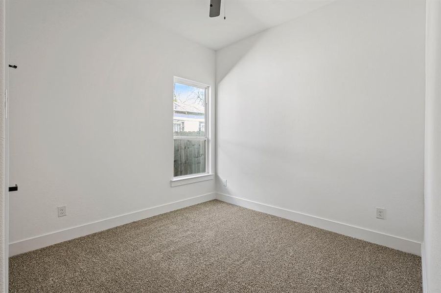 Carpeted spare room featuring a ceiling fan and baseboards