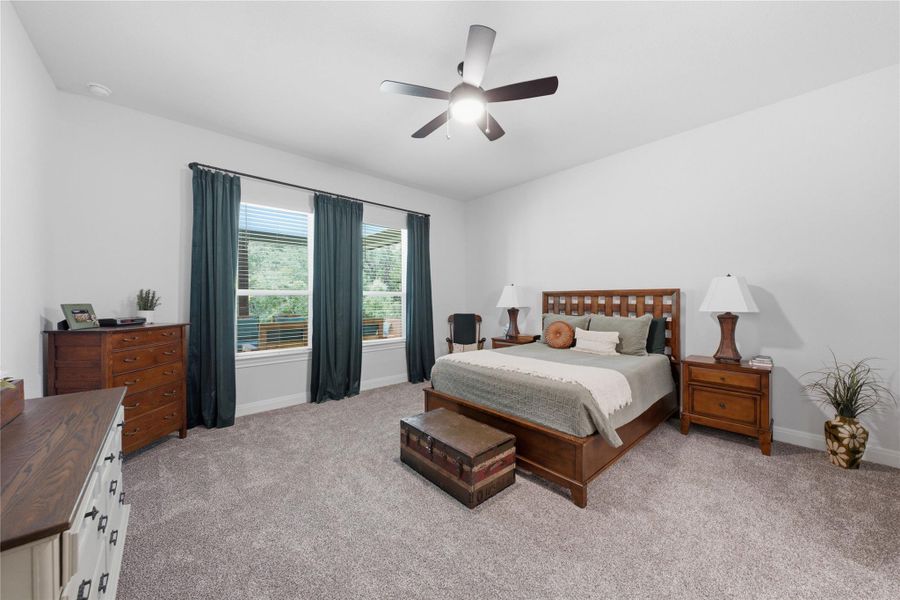 A quiet and comfortable bedroom with a ceiling fan, plush carpet, and ample natural light. A quiet and comfortable bedroom with a ceiling fan, plush carpet, and ample natural light.