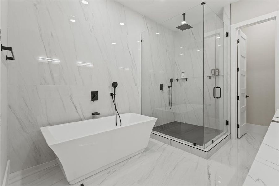 Full bath featuring light marble finish floors, a freestanding tub, and a marble finish shower