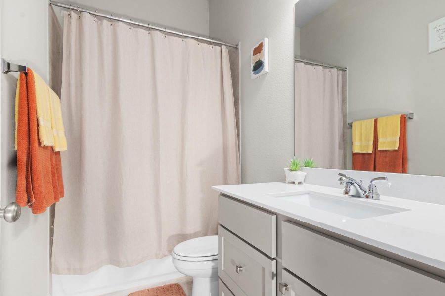 Bright and modern bathroom featuring a sleek white vanity with ample storage, a large mirror, and a tub.