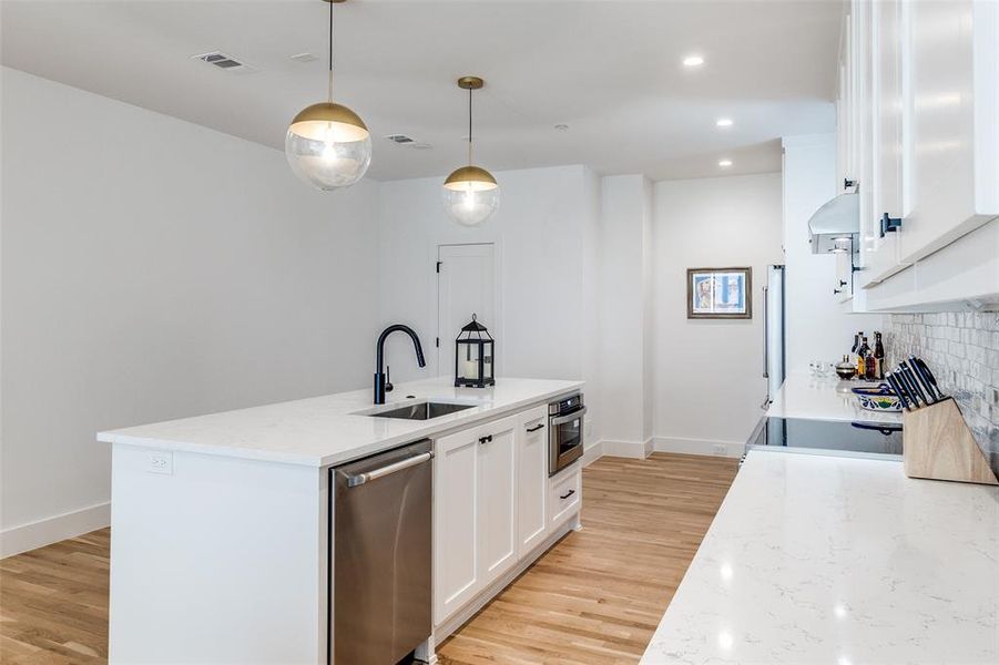 Kitchen featuring white cabinets, decorative light fixtures, light stone counters, appliances with stainless steel finishes, and recessed lighting Kitchen featuring white cabinets, decorative light fixtures, light stone counters, appliances with stainless steel finishes, and recessed lighting