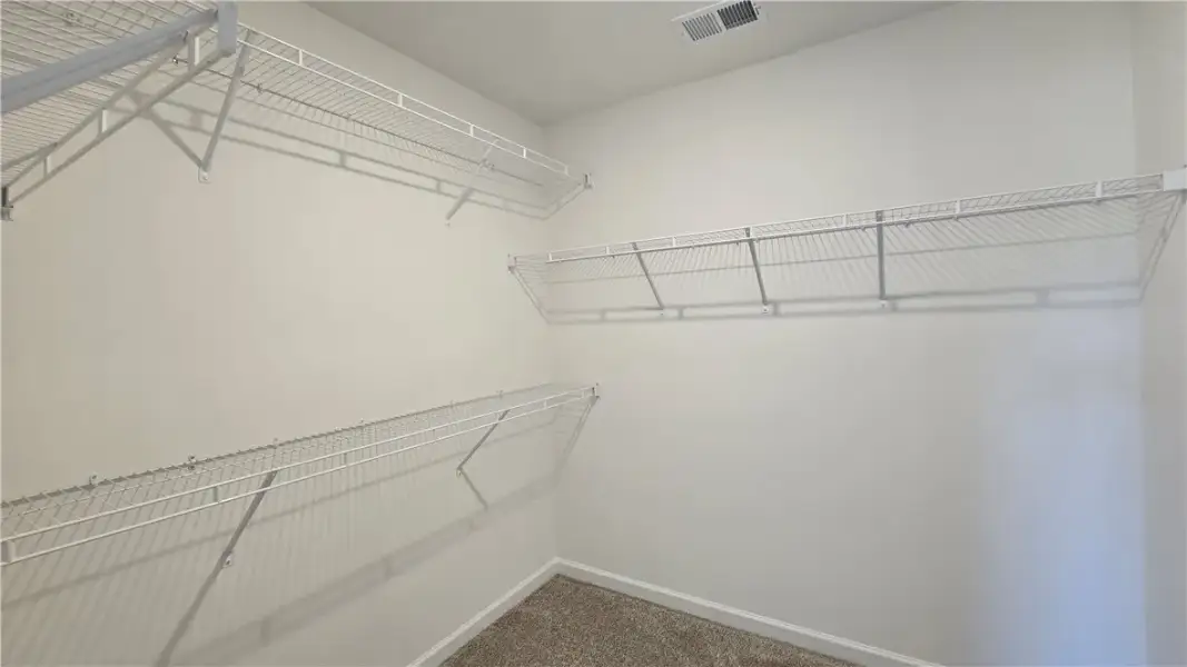 A spacious walk-in closet features built-in wire s