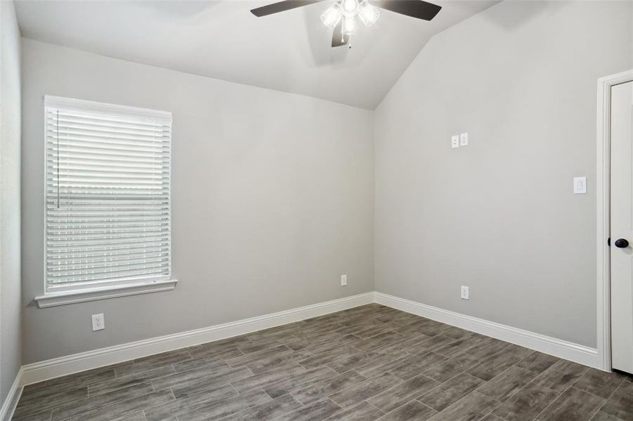 Empty room with ceiling fan, wood-type flooring, and vaulted ceiling