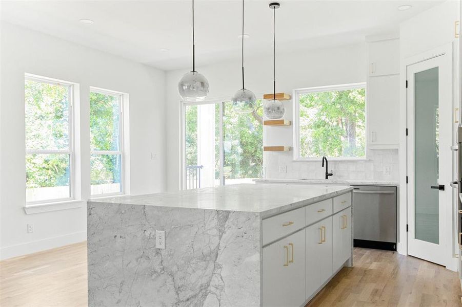 Kitchen with light hardwood / wood-style floors, a kitchen island, decorative light fixtures, tasteful backsplash, and dishwasher