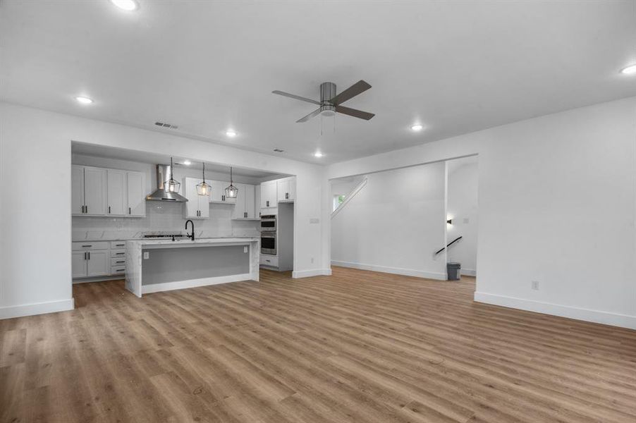 Unfurnished living room featuring sink, light hardwood / wood-style floors, and ceiling fan