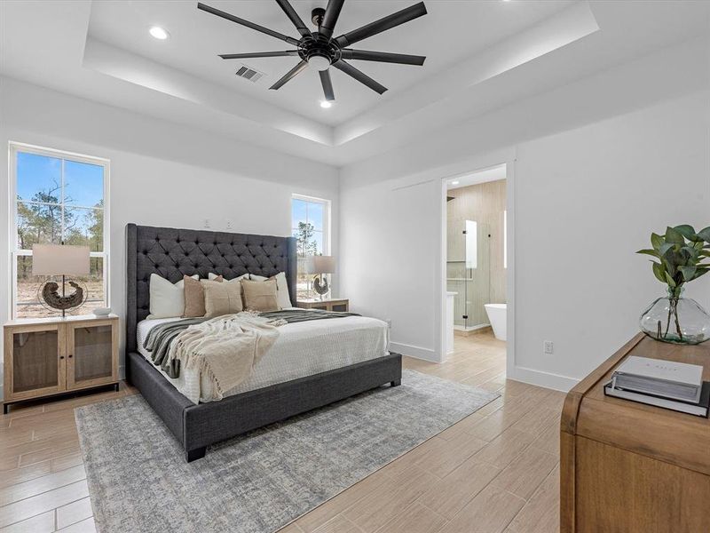 Primary bedroom features include; ceiling fan, tray ceiling, and tile flooring