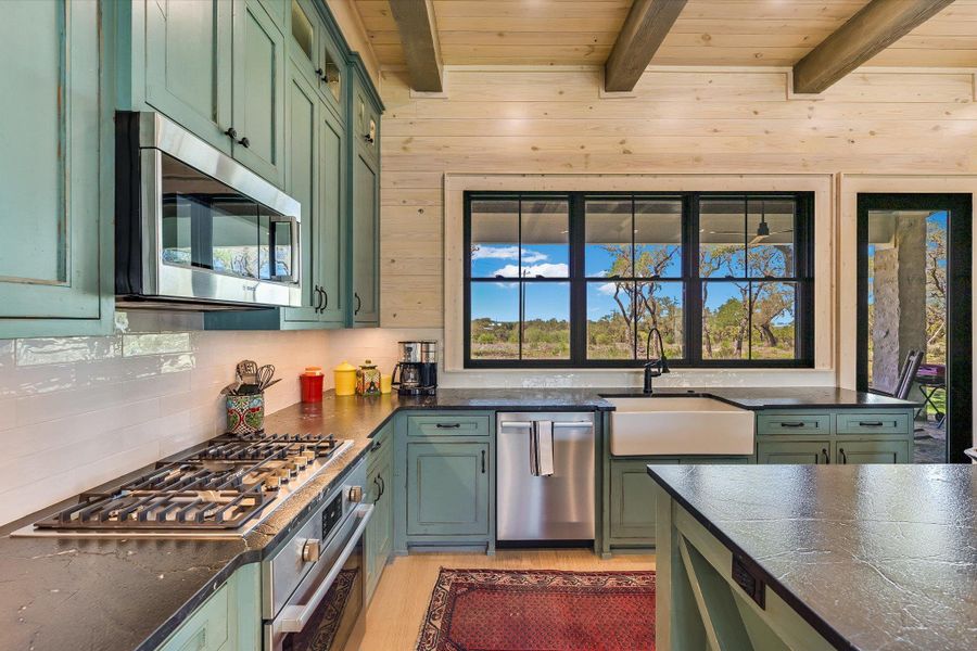 Kitchen featuring green cabinets, stainless steel appliances, a wood ceiling with exposed beams, wood walls, and light wood-style flooring