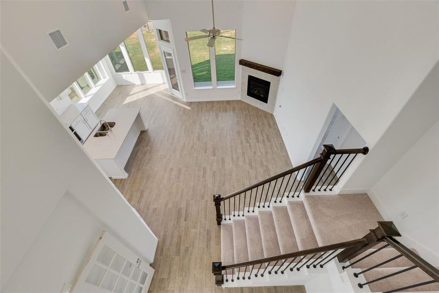 Staircase with ceiling fan, wood-type flooring, and a high ceiling