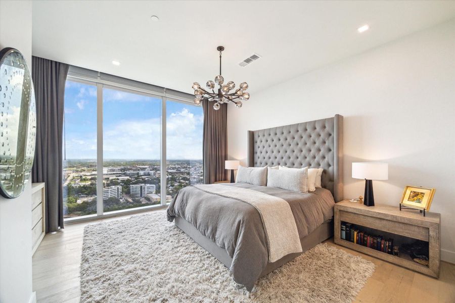 Spacious primary bedroom with both remote-controlled blinds and blackout draperies.