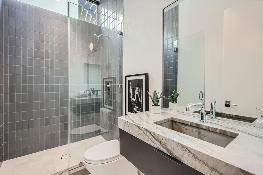 A well-lit contemporary bathroom offers a spacious walk-in shower and a stylish marble-topped vanity. A well-lit contemporary bathroom offers a spacious walk-in shower and a stylish marble-topped vanity.