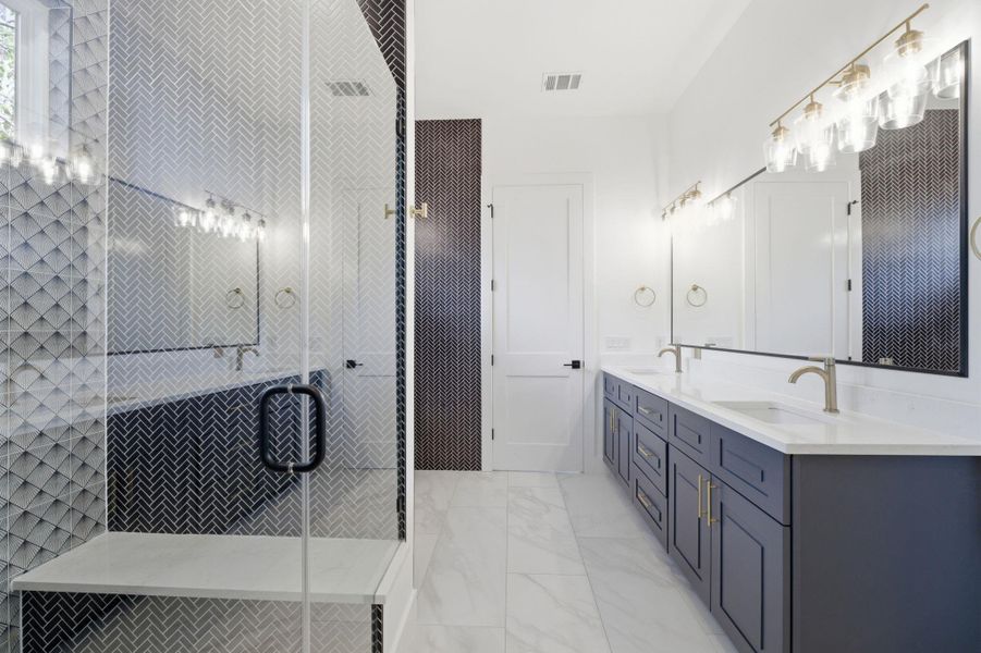 Full bath featuring double vanity, a shower stall, and light marble finish flooring