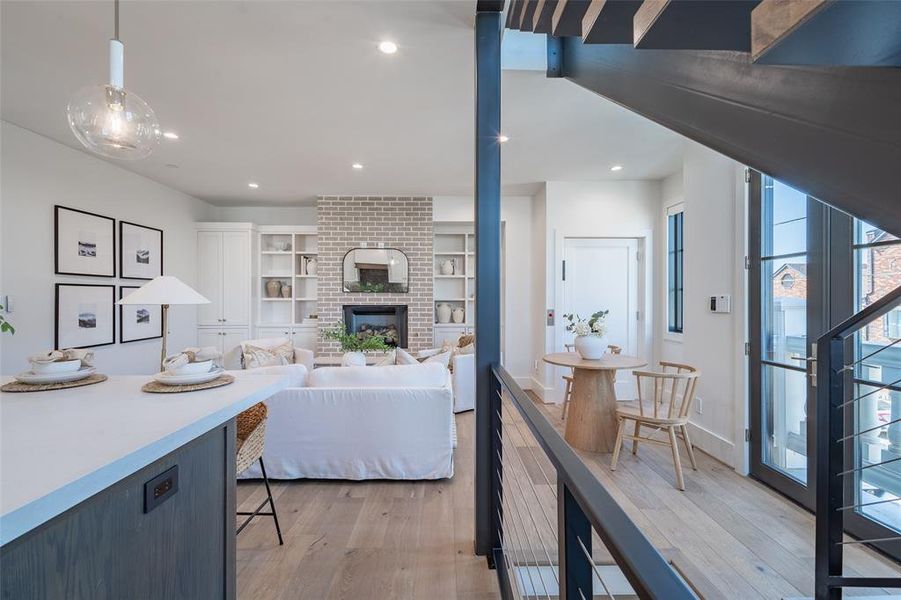 Kitchen with a gas fireplace, built in features, decorative light fixtures, and light hardwood floors