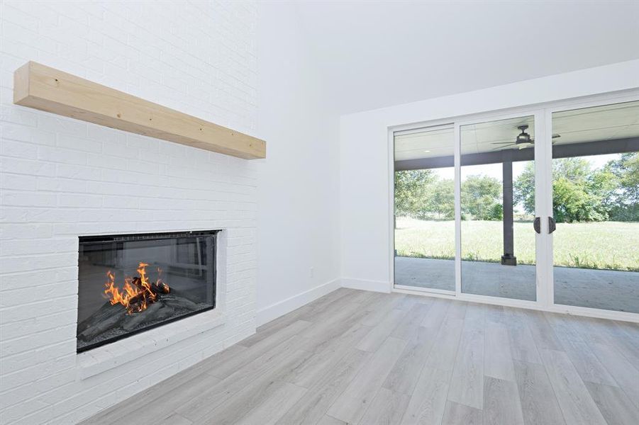Unfurnished living room featuring a fireplace, light wood-type flooring, and ceiling fan
