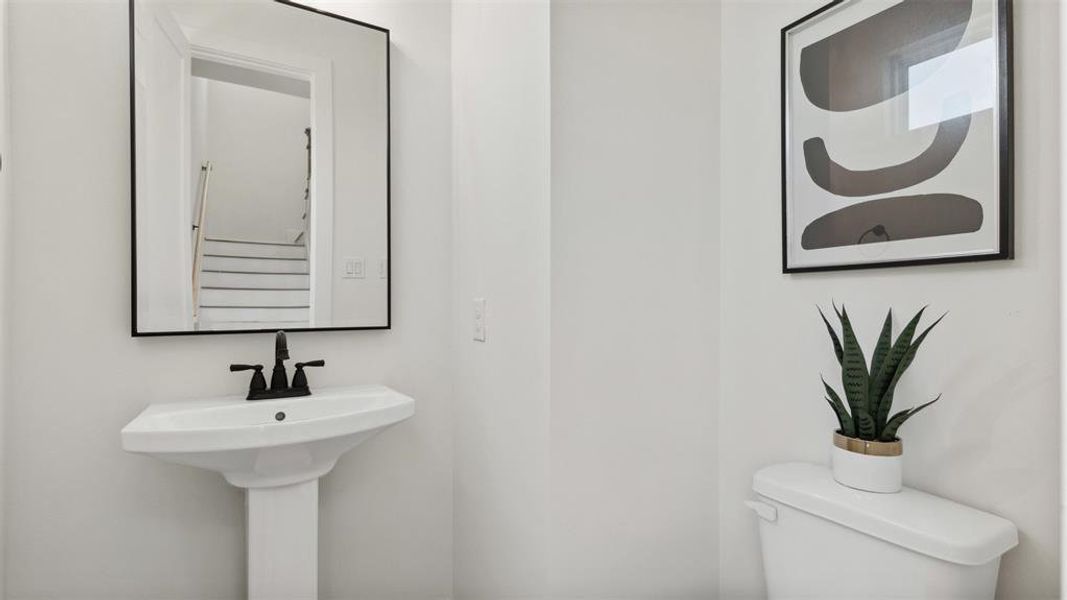 Your modern half-bathroom comes completed with custom paint, featuring a pedestal sink, and a modern framed black matte mirror with overhead lighting. A window allows for rays natural lighting.