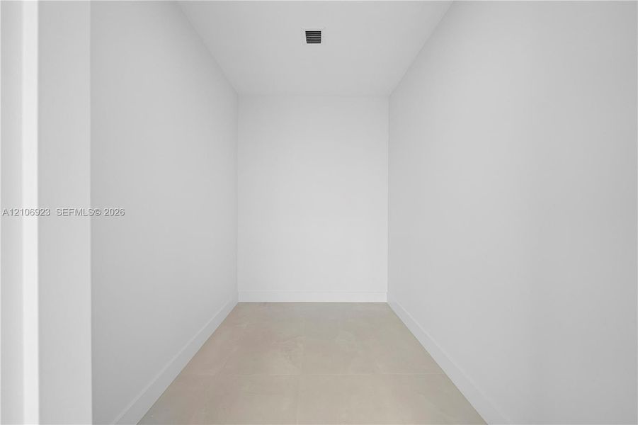 Minimalist interior space featuring neutral wall tones, large-format tile flooring, and recessed ceiling lighting Minimalist interior space featuring neutral wall tones, large-format tile flooring, and recessed ceiling lighting