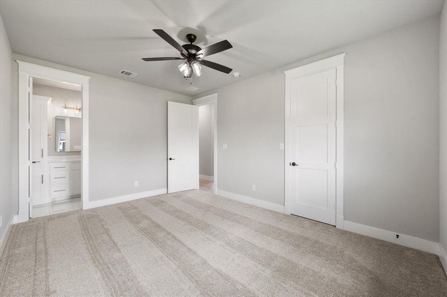 Spacious bedroom featuring light neutral wall paint and plush carpeting