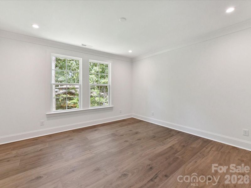 Lots of natural light  in secondary bedroom with large windows, peaceful wooded views, and ample space for guests or family.