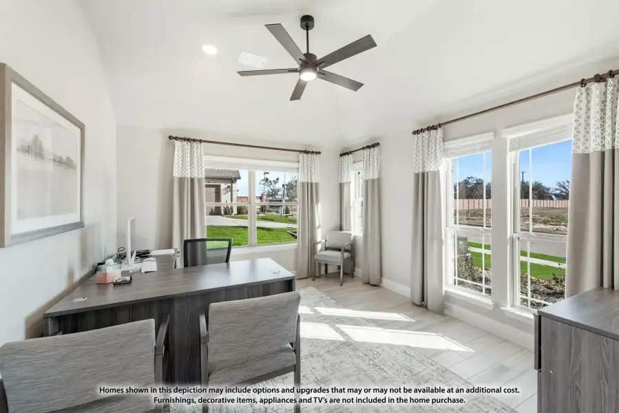 Home office with dark wood desk, ceiling fan, vaulted ceiling, and large windows with natural light
