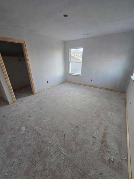 Unfurnished bedroom with a walk in closet and baseboards
