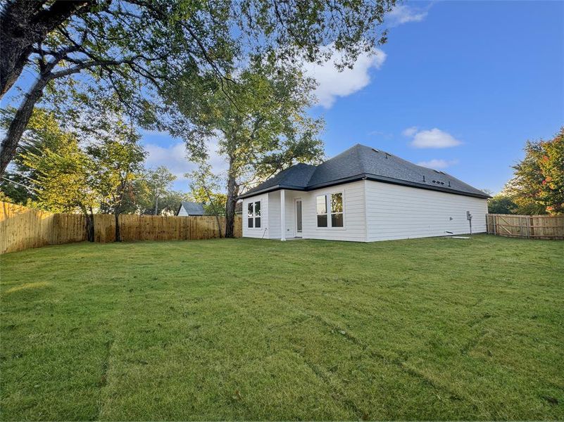 Back of house featuring a fenced backyard and a shingled roof