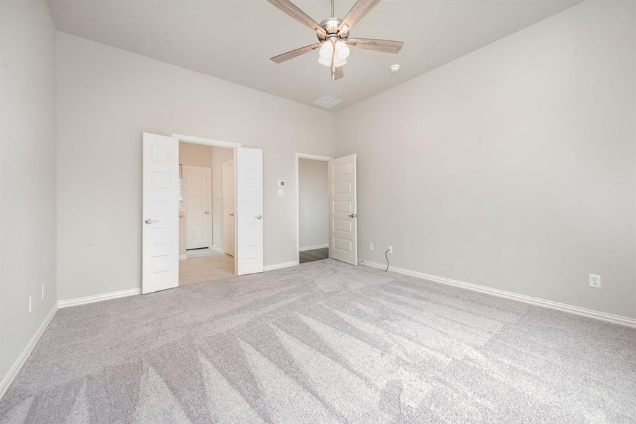 Unfurnished bedroom with ceiling fan and light colored carpet