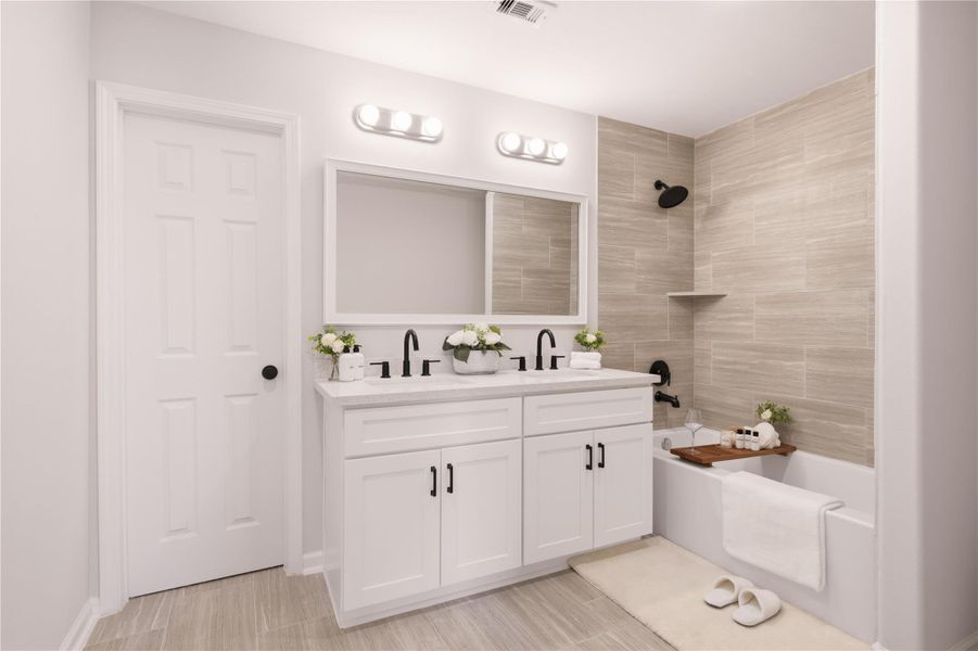 Primary bathroom. Spa-like retreat with a quartz-topped custom vanity with dual sinks. Beautiful tiles, elegant fixtures, and high-arc faucets. Indulge and relax in the upgraded bathtub after a long day of hard work. From a previous project with a similar floor plan Primary bathroom. Spa-like retreat with a quartz-topped custom vanity with dual sinks. Beautiful tiles, elegant fixtures, and high-arc faucets. Indulge and relax in the upgraded bathtub after a long day of hard work. From a previous project with a similar floor plan