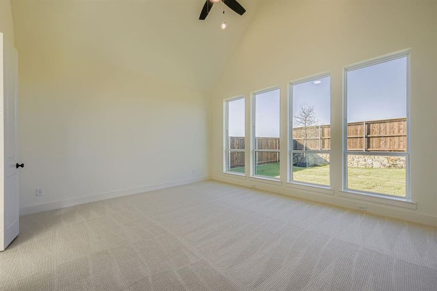 Empty room with high vaulted ceiling, light colored carpet, a ceiling fan, and recessed lighting