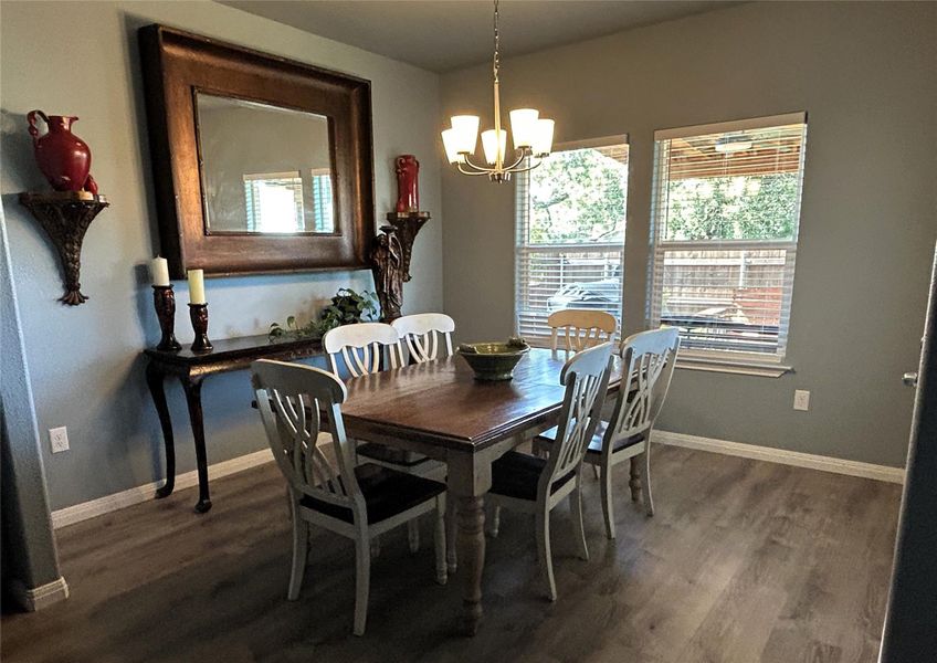 Natural light illuminates this dining area, highlighting the warm wood flooring and elegant chandelier. Natural light illuminates this dining area, highlighting the warm wood flooring and elegant chandelier.