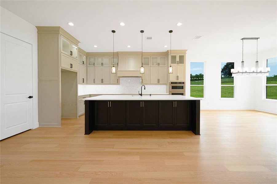 Dual tone kitchen with light wood-style flooring, a large island with sink, glass insert cabinets, a chandelier, and dual tone cabinets