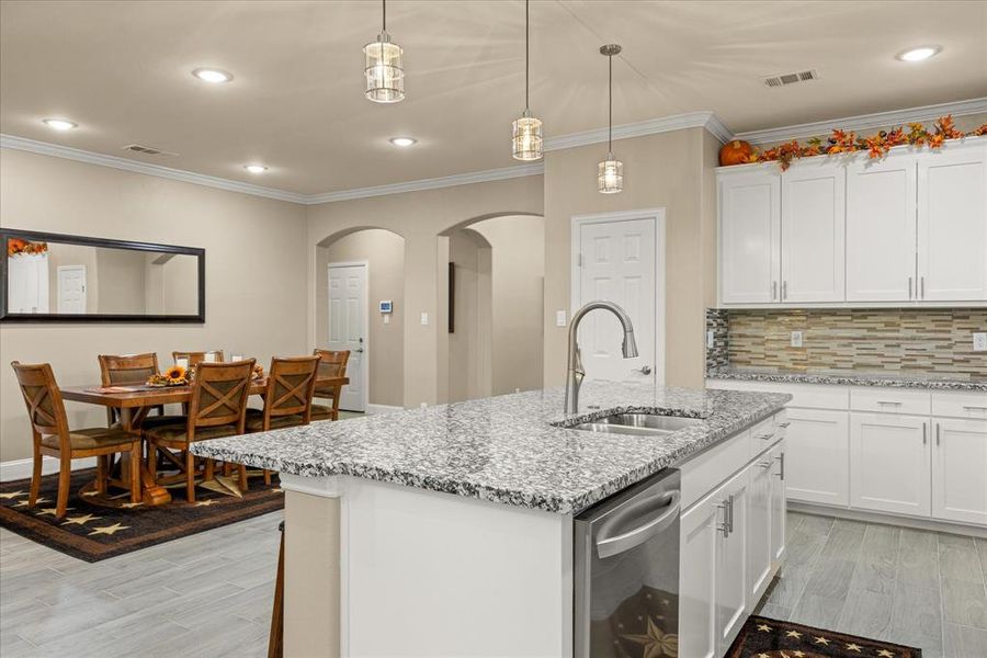 Kitchen with backsplash, recessed lighting, crown molding, white cabinets, and light stone countertops Kitchen with backsplash, recessed lighting, crown molding, white cabinets, and light stone countertops