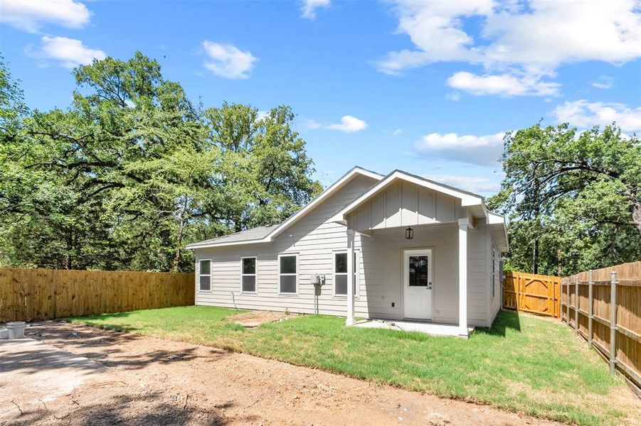 Exterior showcasing light gray siding, a covered patio, and a secured wooden fence enclosing the property Exterior showcasing light gray siding, a covered patio, and a secured wooden fence enclosing the property