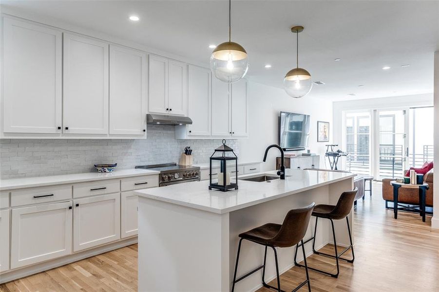 Kitchen featuring white cabinetry, light wood-style floors, decorative light fixtures, decorative backsplash, and recessed lighting Kitchen featuring white cabinetry, light wood-style floors, decorative light fixtures, decorative backsplash, and recessed lighting