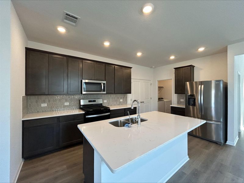Kitchen featuring backsplash, stainless steel appliances, light stone countertops, a kitchen island with sink, and recessed lighting Kitchen featuring backsplash, stainless steel appliances, light stone countertops, a kitchen island with sink, and recessed lighting