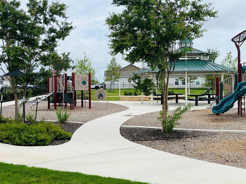 An inviting neighborhood playground features structured play equipment and a central pavilion alongside paved walkways.