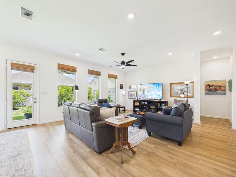 The wall of windows, french door leading to the covered back patio, recessed lighting, ceiling fan and beautiful LVP flooring make this living room a great space to relax, entertain and enjoy! Through the hallway off the living room is the private Primary Retreat.
