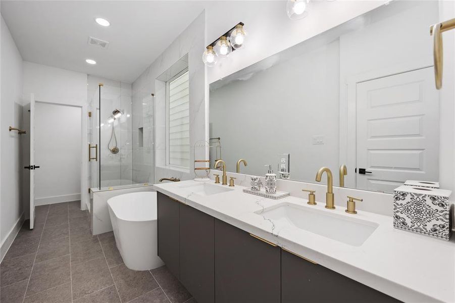 Take a look at this lovely bathroom - sleek white quartz countertops, dual sinks with brushed gold finish, a soaking tub, and a separate glass enclosed shower complete this bath. Modern custom cabinets provide ample storage for all your needs.