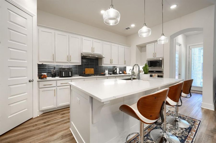 Kitchen featuring white cabinets, sink, a center island with sink, and stainless steel appliances