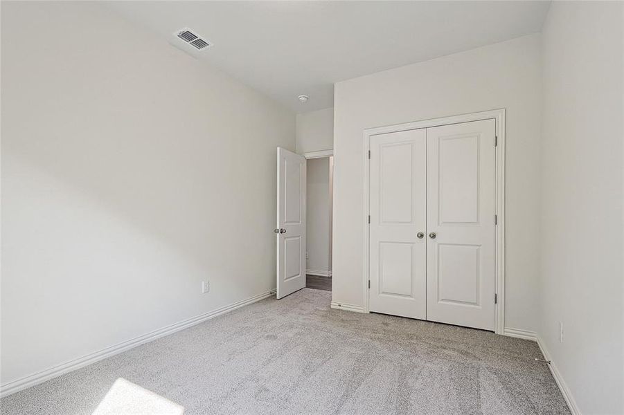 Unfurnished bedroom featuring light carpet and a closet